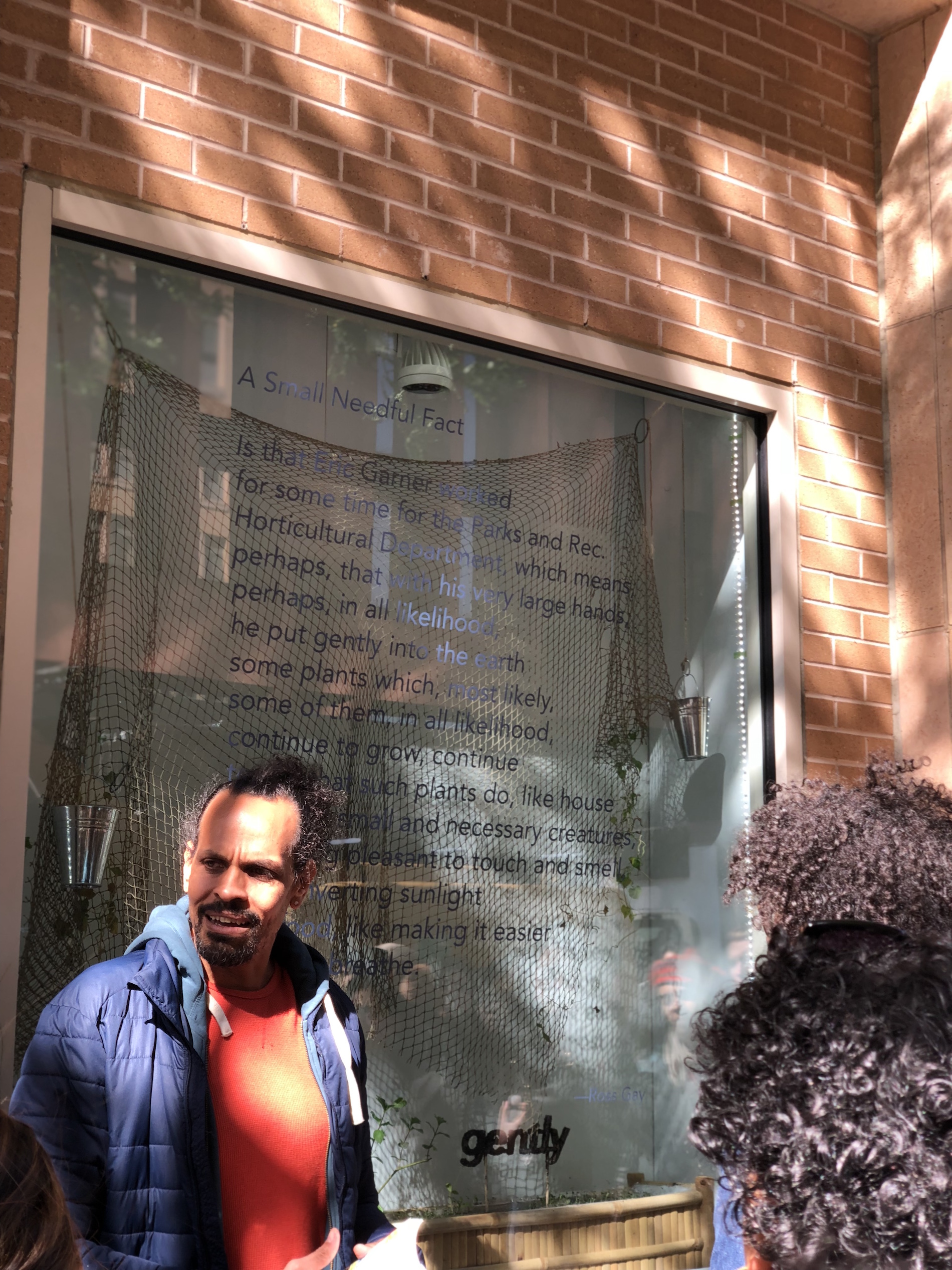 Ross Gay stands in front of window displaying his poem